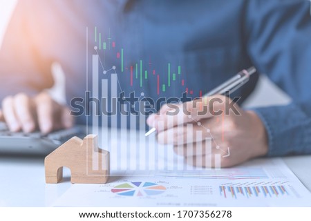 Concept of Property investment and house mortgage financial. A business man, agent calculating income, sales, 
or house dept while economy crisis effect from Coronavirus pandemic. Stock market graph. Royalty-Free Stock Photo #1707356278