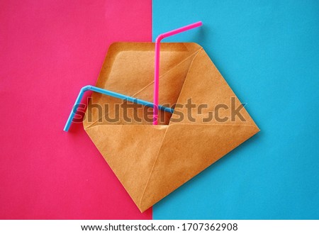 A brown envelope with two cocktail sticks in it on a colorful background, blue and fuchsia background colors, flat lay items
