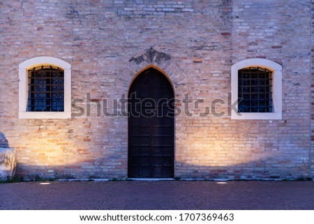 Door and windows of the facade of the 14th-century town hall of Portogruaro, a Gothic building. Wall of bricks. Night photography.