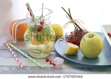 Refreshing cocktail, detox water from organic fruits and berries, mint leaves in glass jugs on a wooden table, healthy nutrition