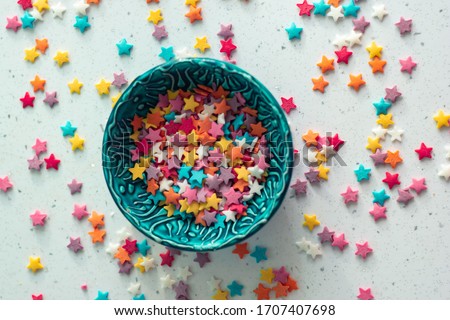Sprinkling baking in the form of stars in a textured turquoise ceramic bowl.