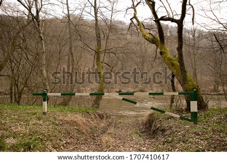 Green and white wooden barrier in a forest near the river early in the spring