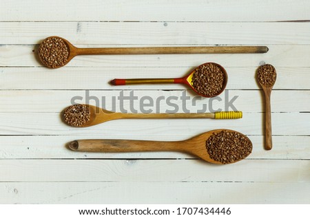 buckwheat on wooden spoons of different sizes on light wooden boards