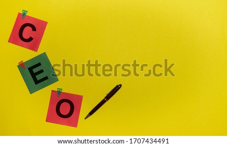 CEO (Chief Executive Officer) acronym on red and green sticky notes and pen on yellow background