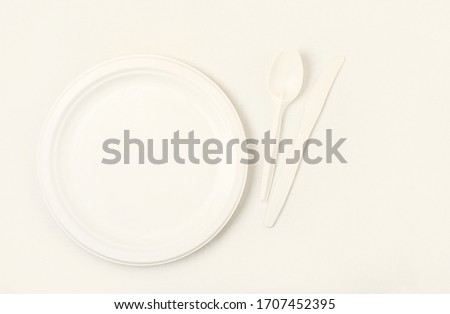 Clean empty plates, cutlery, spoon and knife, on a light background. Eco-friendly biodegradable cookware. Made from corn starch. Ecology concept