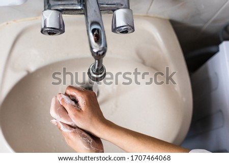 Washing of hands with soap under running water.