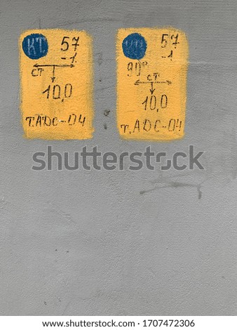 Yellow signs with blue circles on the gray wall looks like eyes