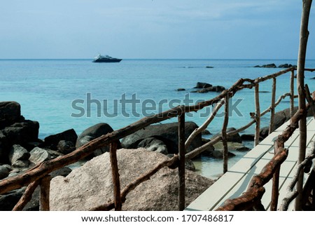 
wooden walkway over the blue sea, in the background you can see a cruise ship