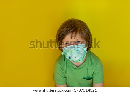 Blond boy in a medical mask on a yellow background with copy space