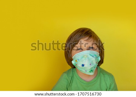 Little boy in medical mask on the yellow background with copy space