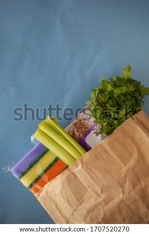 Products from the store in paper pocket. Coronovirus go away. Buckwheat, greens and sponges. Photographed on a bare background.