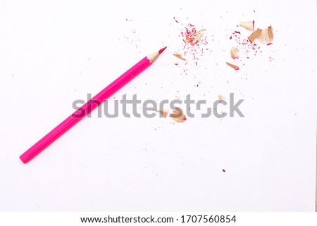 one sharpened pink pencil lies with its shavings on a white background
