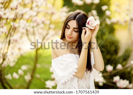 Beauty Romantic Girl Outdoors. Portrait of a happy girl near a blossoming magnolia tree in spring