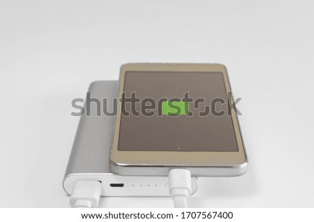 Display with sign of  recharging smartphone battery recharging  from powerbank  on  white background. External solute for charging devices for travel .