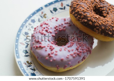 Two donuts on a plate with flower pattern closeup.