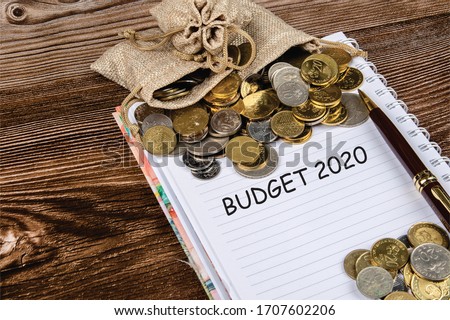 Bag of coin and note book for record on wooden table with word BUDGET 2020. - Saving Concept.