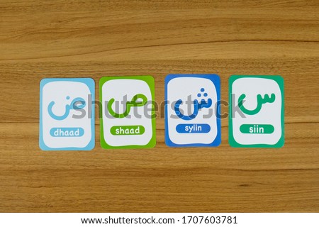 Arrangement of Arabic letters and spelling cards on a wooden table for children's games (top view)