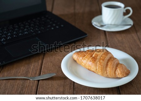 Coffee and coffee beans with croissant bread on a wooden table