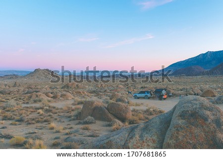 View of beautiful pink & purple sunset over rocky desert while camping/overlanding with off roading vehicle and trailer Royalty-Free Stock Photo #1707681865