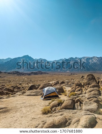 Tent set up in front of Mt.Whiney in rocky Californian desert under clear blue sky. Overlanding/camping under a hot sun in dusty rocky desert, facing Mt. Whitney