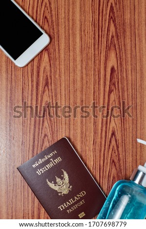 Top view picture of Thailand passport with smartphone and alcohol gel on wood table background,Copy Space