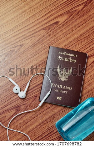 Top view picture of Thailand passport with alcohol gel and Headphones on wood table background.
