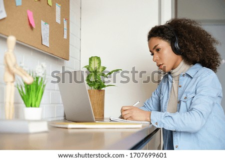 African teen girl college student, school pupil, remote worker learning with online tutor studying at home office desk watching webinar, make video conference zoom call on computer distance elearning. Royalty-Free Stock Photo #1707699601