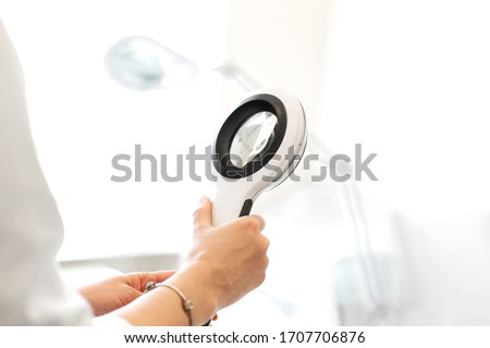 Doctor trichologist dermatologist holding a magnifying glass for examination of a patient. Royalty-Free Stock Photo #1707706876