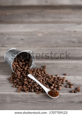 Arabica coffee beans in a small miniature bucket. ground coffee in a white ceramic spoon on a wooden background