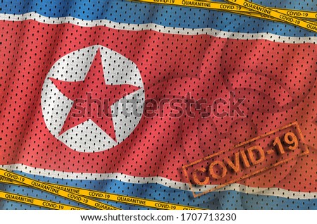North Korea flag and Covid-19 biohazard symbol with quarantine orange tape and stamp. Coronavirus or 2019-nCov virus concept