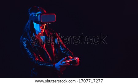 emotional girl in 3D virtual reality glasses with a joystick plays a modern computer game