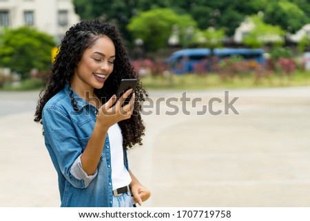 Funny brazilian young adult woman using a smart phone voice recognition outdoor in summer in city