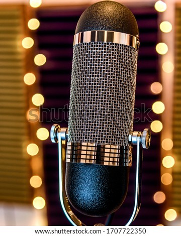 A classic chrome ribbon microphone in recording studio setting with bokeh lights in the background