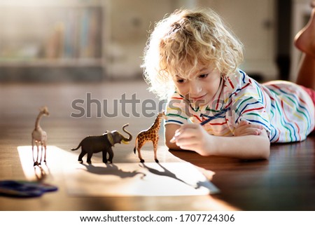 Child shadow drawing animals. Kids play at home. Fun crafts for kindergarten children. Little boy painting giraffe and elephant in sunny bedroom. Games and art during coronavirus quarantine lockdown.