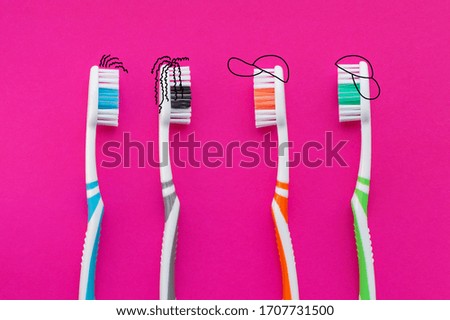 Colorful toothbrushes in the form of cartoon characters on a pink background. The view from the top. The concept of dental health.