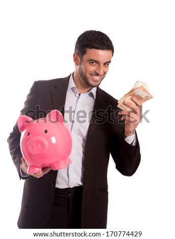 vertical portrait of a happy business man wearing a suit holding a piggy bank and money smiling at the camera on a white background