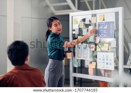 asian ux developer and ui designer presenting mobile app interface design on whiteboard in meeting at modern office.Creative digital development mobile app agency.digital transformation