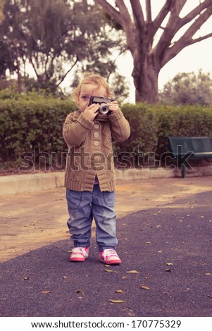 Cute little baby holding vintage camera. Photo in old color
