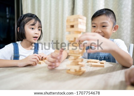 Kids playing and stay at home, children funny and joyful wood blocks game on table, brother and sisters in family, cute Asian kids smile and happy in this activity, boy and girl child cheerful game