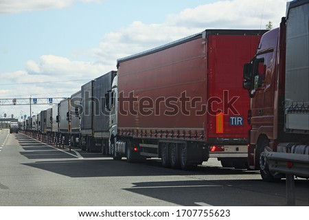 Drivers strike, big queue of trucks with semi-trailers to the sanitary and weight control point in Sunny summer day, rear side view in perspective Royalty-Free Stock Photo #1707755623