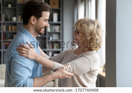 Elderly mother admires matured adult son looking at him smiles enjoy long awaited meeting after separation feels happy and proud, side view. Loving grown up child visited mom, familial ties concept Royalty-Free Stock Photo #1707760408
