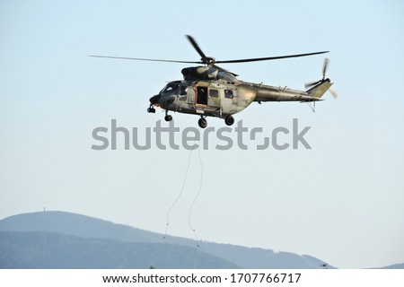 Two ropes hanging from a rescue military helicopter, blues sky and the mountains in the background