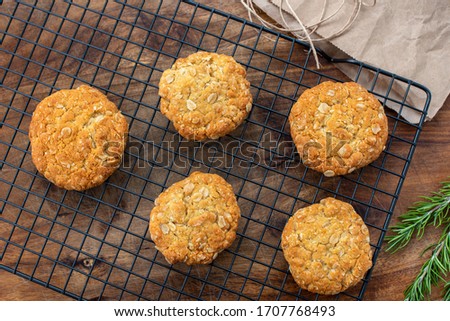 Anzac biscuits, a traditional oat and coconut Australian cookie made with golden syrup, pictured with rosemary a symbol of remembrance associated with Australia's WW1 soldiers at Gallipoli, flat lay