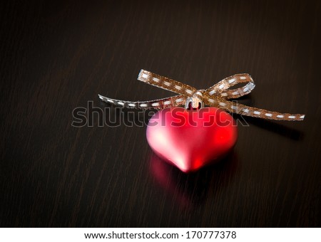 Glowing red heart on dark wooden background
