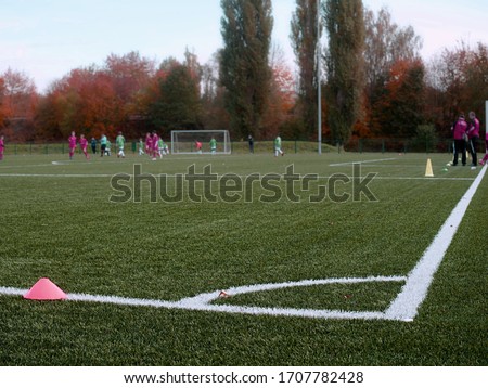 Selective focus to arker cones used for soccer training on green artificial turf with blurry kid players training background