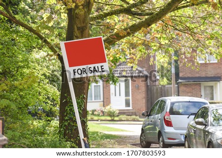 For sale sign outside house on a residential street in uk