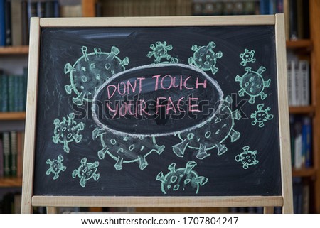 Dont touch your face. Outbreak Warning. written white chalk on blackboard in connection with epidemic coronavirus worldwide Covid 19 pandemic Text on black background free space drawn virus bacteria