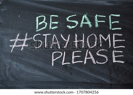 Hashtag stay at home. Outbreak Warning. written white chalk on blackboard in connection with epidemic of coronavirus worldwide. Covid 19 pandemic Text on black background with free space.