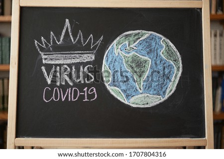 Planet Earth in danger Outbreak Warning. written white chalk on blackboard in connection with epidemic of coronavirus worldwide. Covid 19 pandemic Text on black background 