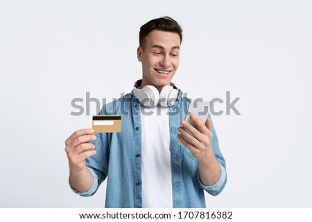Online shopping concept. Young man in headphones with credit card and smartphone